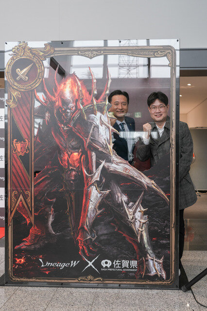 「リネージュ」シリーズ全作に登場する「デスナイト」と一緒に写真が撮れるフォトスポットで記念撮影する佐賀県知事の山口祥義氏、NC Japan事業統括本部長の金 埈範（キム ジュンボム）氏